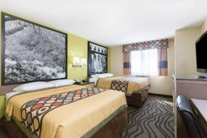 a hotel room with two beds and a flat screen tv at Super 8 by Wyndham Brunswick/St Simons Island Area in Brunswick