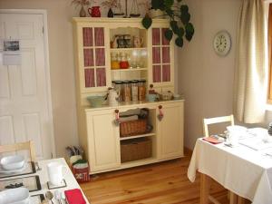 una cocina con una cabaña y una mesa con mesa en Innisfree Cottage, en Eyam