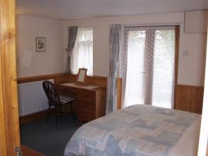 1 dormitorio con cama, escritorio y silla en The Coach House, en Ledbury