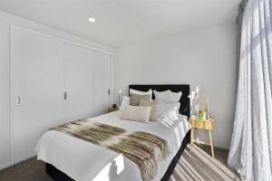 a white bedroom with a large bed with a fur blanket at Urban Diamond in Christchurch