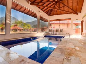 an indoor swimming pool in a house with windows at Pousada Aldeia Manacás in São Bento do Sapucaí