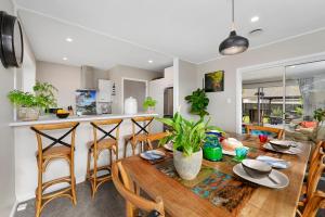 a kitchen and dining room with a wooden table and chairs at Leave of Absence - Christchurch Holiday Home in Christchurch