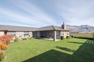 ein Haus mit einem Rasen davor in der Unterkunft Infinity Views - Modern Wanaka Holiday Home in Wanaka