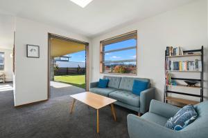 ein Wohnzimmer mit Sofa und Tisch in der Unterkunft Infinity Views - Modern Wanaka Holiday Home in Wanaka
