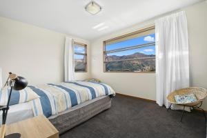 ein Schlafzimmer mit einem Bett und einem großen Fenster in der Unterkunft Infinity Views - Modern Wanaka Holiday Home in Wanaka