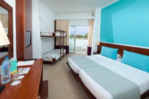 - une chambre avec un grand lit et un mur bleu dans l'établissement Palm Beach Club Marmara Djerba, à Midoun
