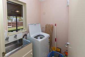 a laundry room with a washing machine and a sink at Kepler Retreat - Te Anau Holiday Home in Te Anau