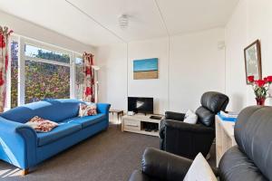 a living room with a blue couch and two chairs at Pakawau Beach House - Golden Bay Holiday Home in Pakawau
