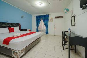 een slaapkamer met een groot bed en een bureau bij RedDoorz Syariah near Jalan Asahan Pematang Siantar in Pematangsiantar