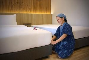 a woman in a hotel room making a bed at Nine Hotel Chiangmai in Chiang Mai