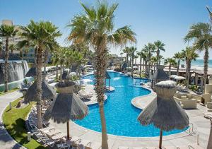 a resort with a pool with palm trees and umbrellas at Vidanta Puerto Peñasco in Puerto Peñasco