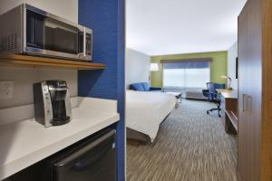 a hotel room with a bed and a microwave at Holiday Inn Express & Suites Grand Rapids Airport North, an IHG Hotel in Grand Rapids