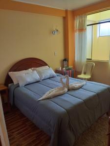a bedroom with a large bed with a blue blanket at Hostal Real Divina in Juliaca