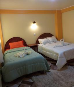 1 dormitorio con 2 camas y toallas. en Hostal Real Divina, en Juliaca