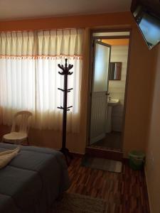 a bedroom with a bed and a mirror and a bathroom at Hostal Real Divina in Juliaca