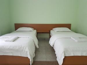 una habitación con dos camas con sábanas blancas en Komodo Boutique Hotel, en Labuan Bajo