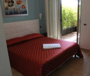 a bedroom with a bed with a red comforter at Hotel Vittorio Emanuele in Floridia