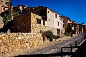 una pared de piedra junto a una calle con edificios en Casa Rural Os Arregueses, en Alquézar
