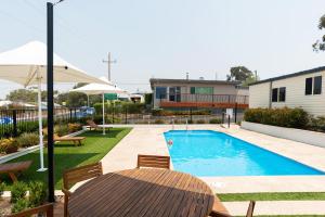 a backyard with a swimming pool and a table and chairs at Crestview Tourist Park in Queanbeyan