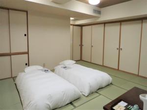 twee witte bedden in een kamer met kasten bij Hotel Tokeidai in Sapporo