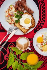 a plate of breakfast food with eggs bacon and a cup of coffee at Zanzibar Queen Hotel in Matemwe