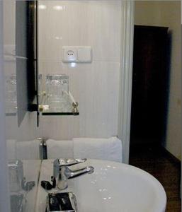 a white bathroom with a sink and a mirror at Hostal Delfina in Madrid