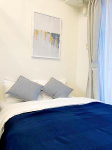 een slaapkamer met een blauw en wit bed met 2 kussens bij OUCHI HOTEL Higashi-Hiratsuka #201 in Hiroshima