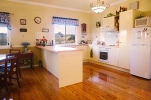 kuchnia z białymi urządzeniami i drewnianą podłogą w obiekcie Milford Country Cottages w mieście Milford