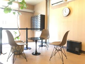 Habitación con sillas, mesa y reloj en Hotel&Co. Sagami en Tokio