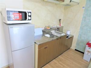 a kitchen with a sink and a microwave on top of a refrigerator at 札幌市中心部大通公園まで徒歩十分観光移動に便利なロケーションs1111 in Sapporo