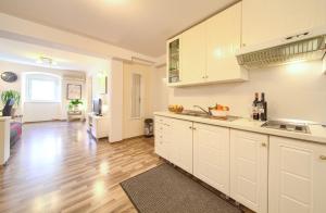uma cozinha com armários brancos e piso de madeira em Apartment City Center em Rijeka