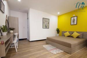 a bedroom with a bed and a yellow wall at Na Homestay in Hue