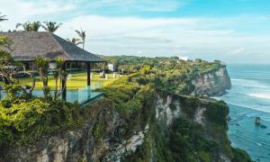 a building on a cliff next to the ocean at The Istana in Uluwatu
