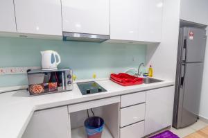 eine weiße Küche mit einer Spüle und einem Kühlschrank in der Unterkunft Centrus Soho Cyberjaya by IdealHub in Cyberjaya