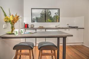 une cuisine avec une table et deux tabourets dans l'établissement Eumundi Cottages - Cottage 2, à Eumundi