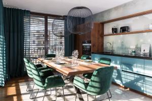 a dining room with a wooden table and green chairs at ANTON Dolomites Hideaway in Brunico