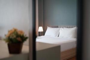 スコータイにあるスコータイ ガーデンのベッドルーム1室(白い枕とランプ付きのベッド1台付)