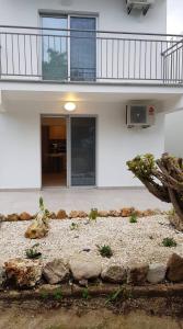 ein weißes Gebäude mit einem Balkon und einem Steingarten in der Unterkunft Polis Herb Garden in Polis Chrysochous