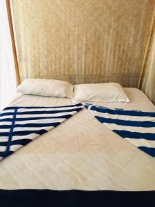uma cama com lençóis e almofadas azuis e brancos em Yoga Culture Palolem em Palolem