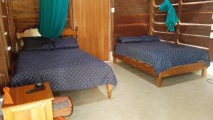 a bedroom with two beds and a wooden wall at Cabanas chaac calakmul in Xpujil