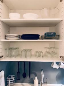 a kitchen shelf with dishes and utensils on it at Petit studio cosy in Bobigny
