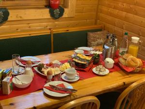 - une table en bois avec des aliments pour le petit-déjeuner dans l'établissement Gaststätte und Pension Zum Torfstich, à Hundshübel