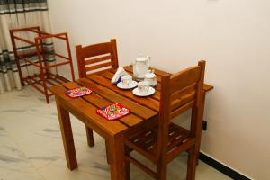a wooden table and chairs with a tea set on it at Verona D' Oro in Dickwella
