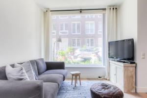 a living room with a couch and a large window at Luxurious ground floor apartment with patio in Amsterdam