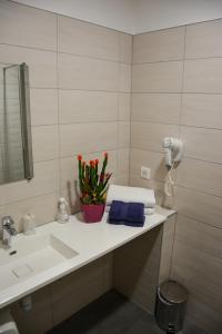 ein Badezimmer mit einem Waschbecken, einem Spiegel und Blumen in der Unterkunft Sud Hotel in Huttenheim