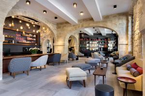 a lobby of a restaurant with chairs and tables at Boutique Hôtel des Remparts & Spa in Aigues-Mortes