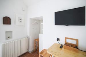 sala de estar con mesa y TV en la pared en Little Room - Camera indipendente nella Torre, en Pontassieve