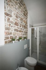 a bathroom with a toilet and a stone wall at Little Room - Camera indipendente nella Torre in Pontassieve