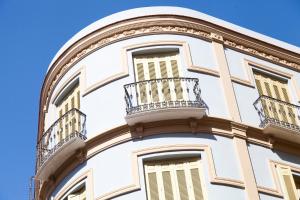 a white building with a balcony and a blue sky at Apartamentos Pinar Malaga Centro in Málaga