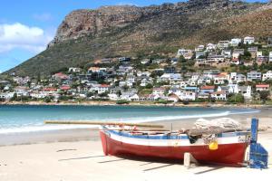 un barco sentado en la playa frente a una ciudad en Fisherman's Watch Cottage, en Ciudad del Cabo